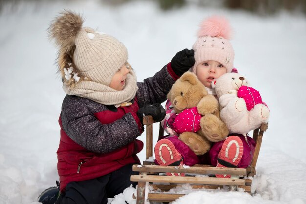 Children ride on a vintage wooden sled against the backdrop of a winter forest