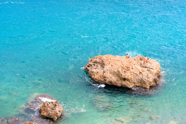 Children on a rock in the blue sea