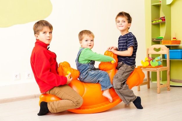 Children on the rocking plastic seesaw in the room indoor