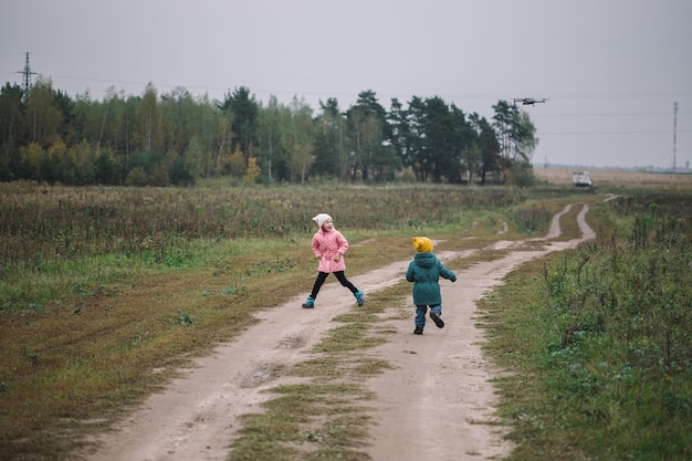 Дети бегут в поле. Дети играют в поле, бегая от летающего дрона