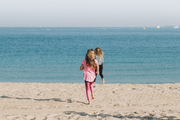 Children Running on the Beach to the Blue Sea