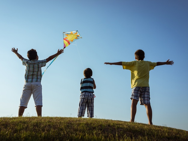 Children running kite on meadow with beautiful sky cloud above