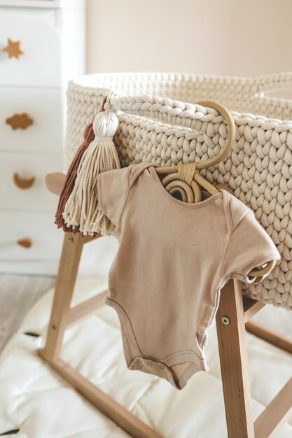 Children's beige bodysuit on a wooden hanger in the nursery