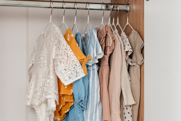 Children's clothes girls' dresses hang on hangers in an open closet dressing room