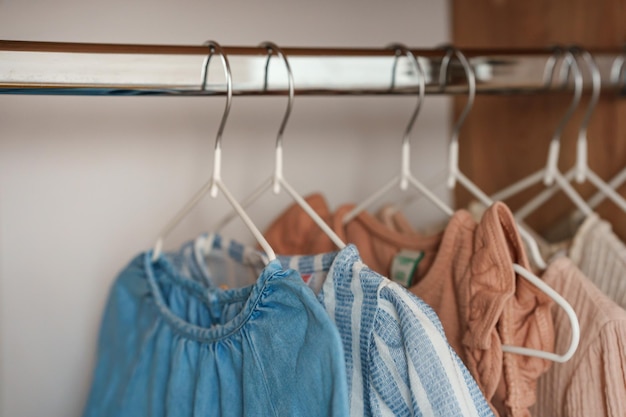 Children's clothes girls' dresses hang on hangers in an open closet dressing room