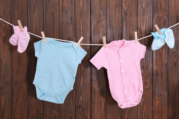 Photo children's clothes on laundry line against wooden background