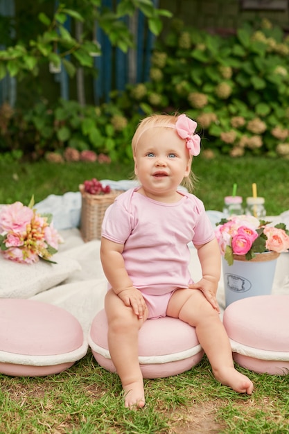 Children's Day, a child girl in the park sits in a basket with macaroons on a summer picnic