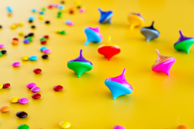 Children's day mini spinning top and colorful chocolates on yellow background