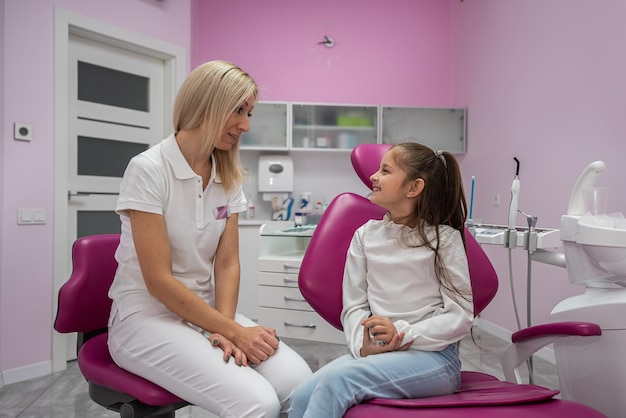 Children's dentist conducts a consultation for a little girl in a dental chair children's dentistry the doctor talks about the importance of oral care