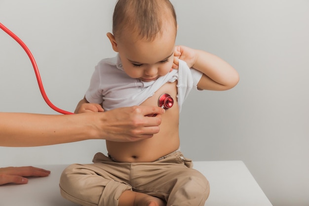 A children's doctor examines a one-year-old boy with a stethoscope at a hospital center. health concept