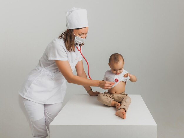 A children's doctor examines a one-year-old boy with a stethoscope at a hospital center. health concept