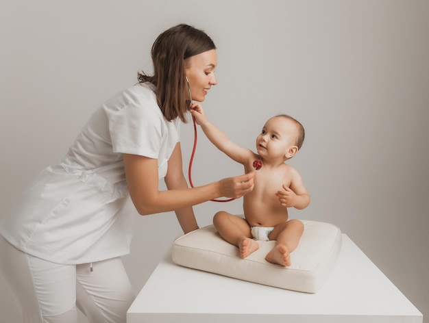 A children's doctor examines a one-year-old boy with a stethoscope at a hospital center. health concept