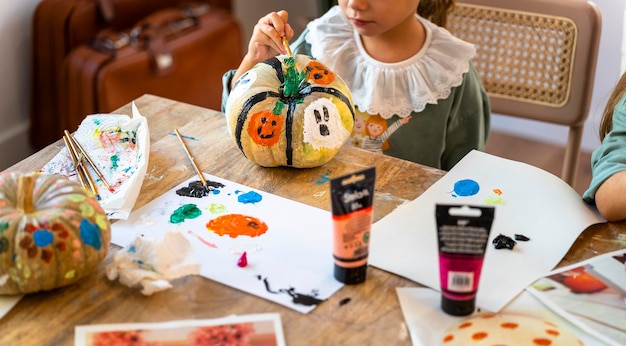 Photo children's drawing class little girl painting ghosts on a pumpkin