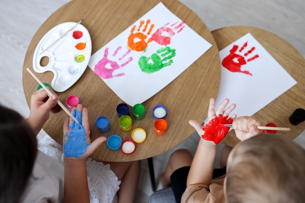 Laboratorio di disegno per bambini i bambini felici fanno impronte di mani con la vernice