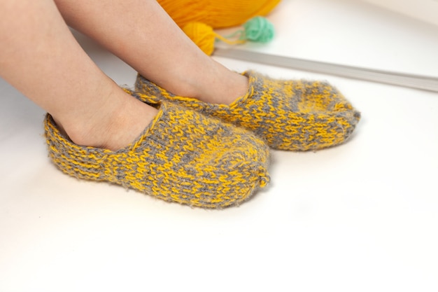 На детских ножках теплые вязаные носки-тапочки желто-зеленого цвета.