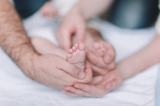 Детские ножки в руках родителей. Концептуальный образ отцовства. Фотография с копией пространства