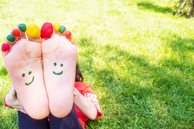 Children's feet with a pattern of paints smile on the green grass. Selective focus. nature.