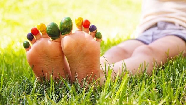 Children's feet with a pattern of paints smile on the green grass. Selective focus. nature.