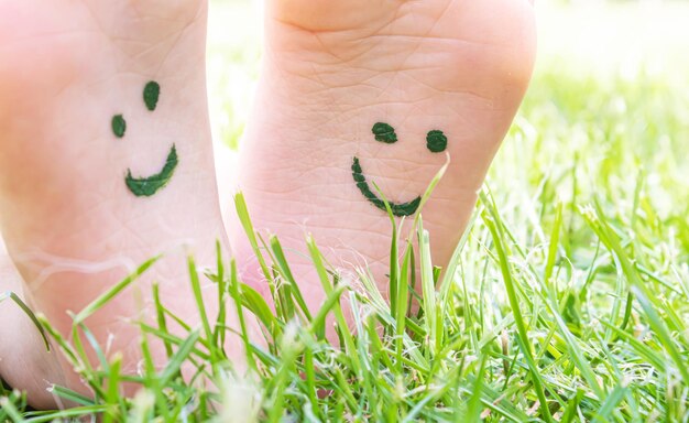 Foto i piedi dei bambini con un motivo di vernici sorridono sull'erba verde natura di messa a fuoco selettiva