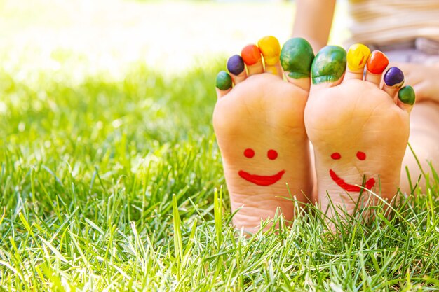 Children's feet with a pattern of paints smile on the green grass. Selective focus.