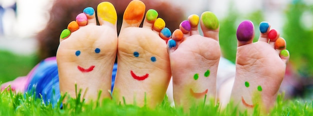 Children's feet with a pattern of paints smile on the green grass Selective focus