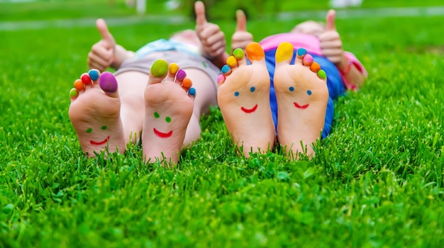 絵の具のパターンを持つ子供の足は緑の草に微笑む選択的な焦点