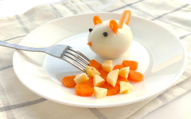 Children's food Funny mouse from a boiled egg closeup on a white plate with cheese and carrots