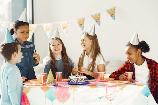 装飾された部屋での子供の面白い誕生日パーティー。ケーキと風船で幸せな子供たち。