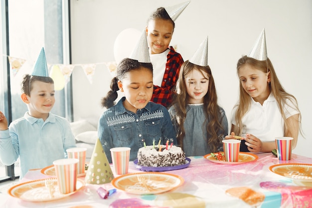 装飾された部屋での子供の面白い誕生日パーティー。ケーキと風船で幸せな子供たち。