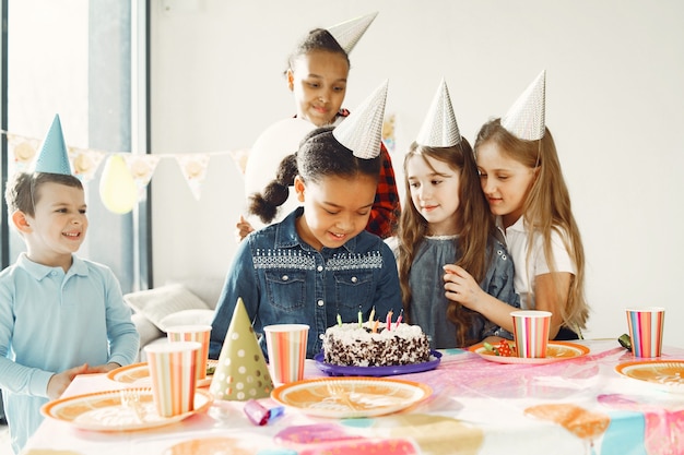 装飾された部屋での子供の面白い誕生日パーティー。ケーキと風船で幸せな子供たち。