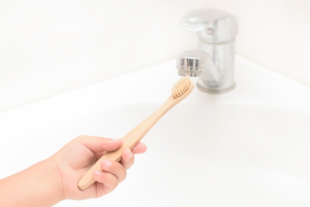 Children's hand wash bamboo toothbrush in the bathroom, concept zero waste, saving the planet from plastic.Communicating children to save the planet