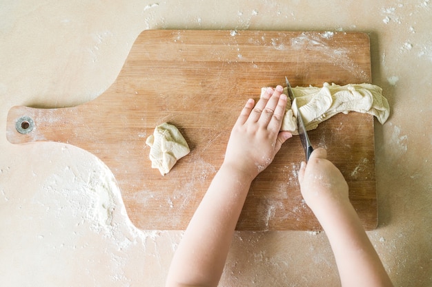 Children's hands cutting raw dough