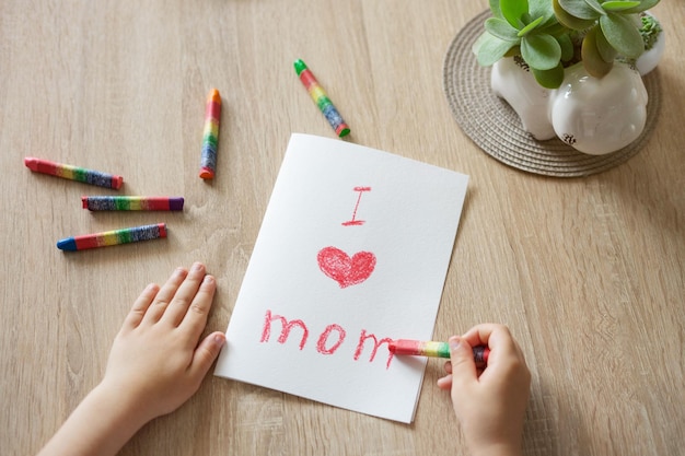 Le mani dei bambini disegnano un biglietto di auguri per la festa della mamma