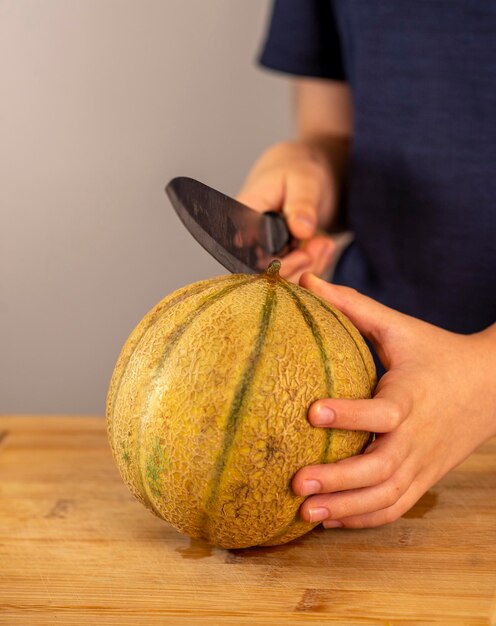 Foto le mani dei bambini tengono un melone e un coltello