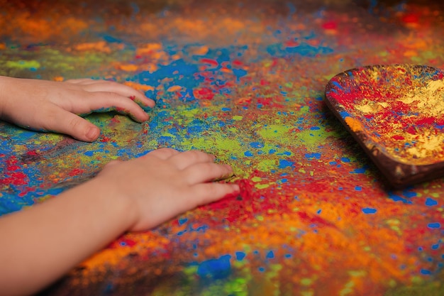 子供たちの手がカラフルな絵の具でテーブルの上に横たわる ホリー