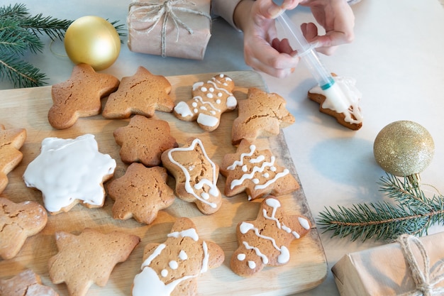 Foto le mani dei bambini preparano i biscotti di panpepato di capodanno su un tavolo di legno. fare i biscotti con un tagliabiscotti. anno nuovo e concetto di natale.