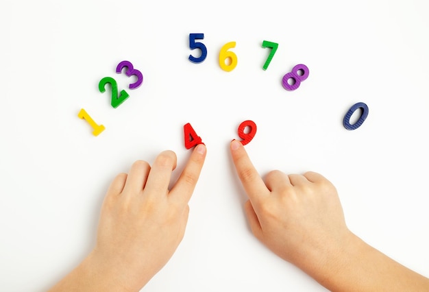 Children's hands move numbers on a white table Learning colors and to count from zero to ten