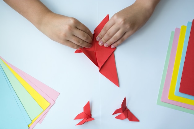 Foto le mani dei bambini fanno una farfalla origami.