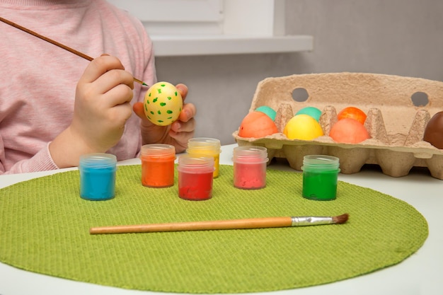 Children's hands paint with paints and Easter eggs and put them in a container