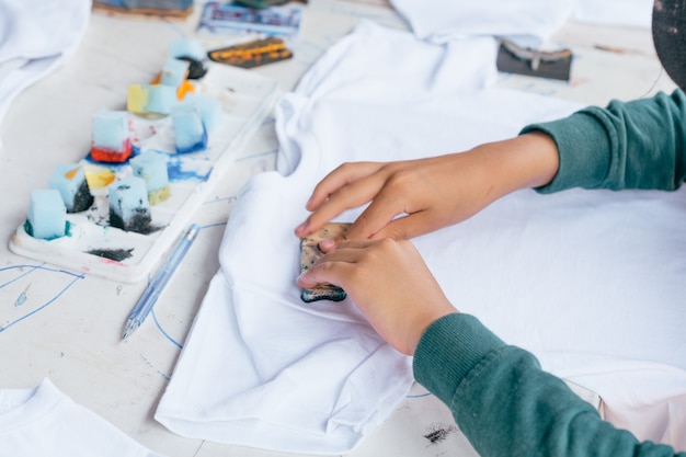 Children's hands painting t-shirts.