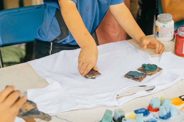 Children's hands painting t-shirts.