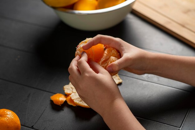 children's hands peel a tangerine over the table