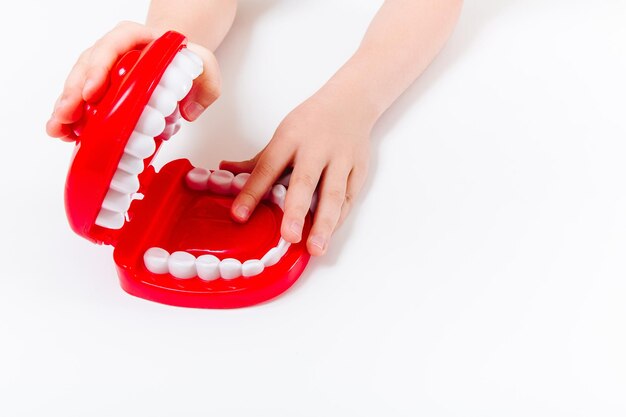 Детские руки, играющие с набором стоматологов Белый фон Медицинская стоматология стоматологическая концепция ухода за полостью рта