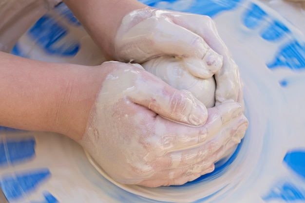 Children's hands potter on a blue circle close-up.