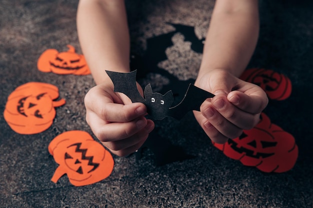 写真 子供の手は、ハロウィーンの紙から装飾を準備します 休日の準備