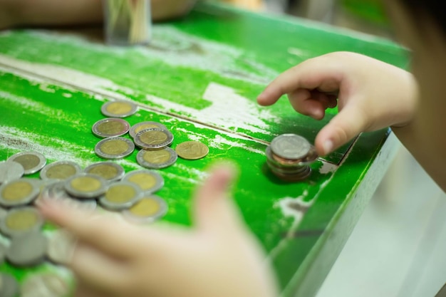 Children's hands putting money coins to a stack of coins on the table concept Saving money wealth and financial Personal finance management loan for a home diagram chart earnings to plan profit