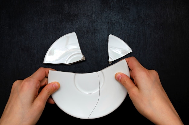 Children's hands stack the fragments of a plate together.