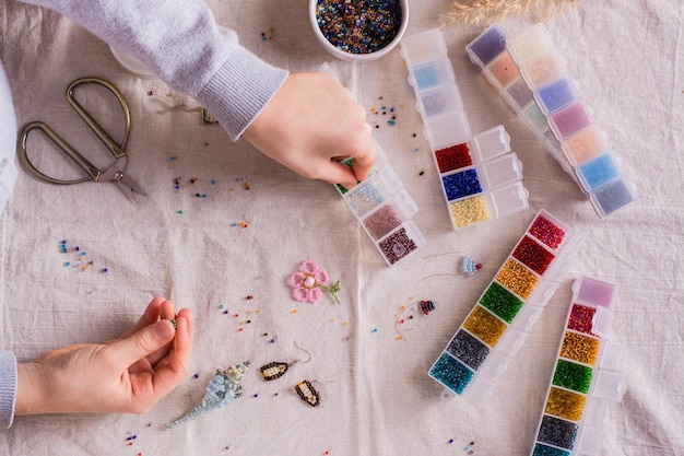 Children's hands take a bead and boxes with beads for weaving a
bracelet top view shildren's hobby