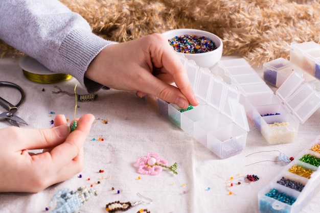 Children's hands take a bead and boxes with beads for weaving a bracelet