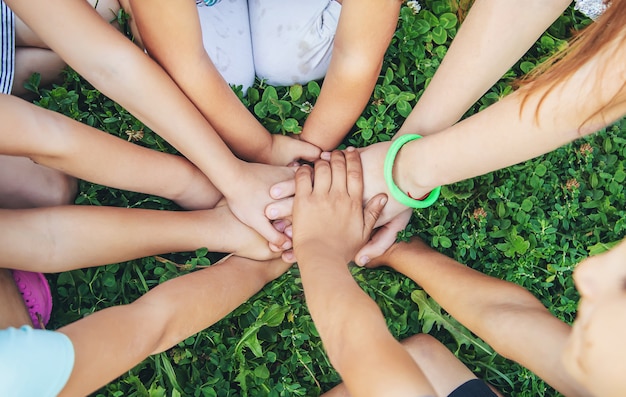 Children's hands together on a background of grass.